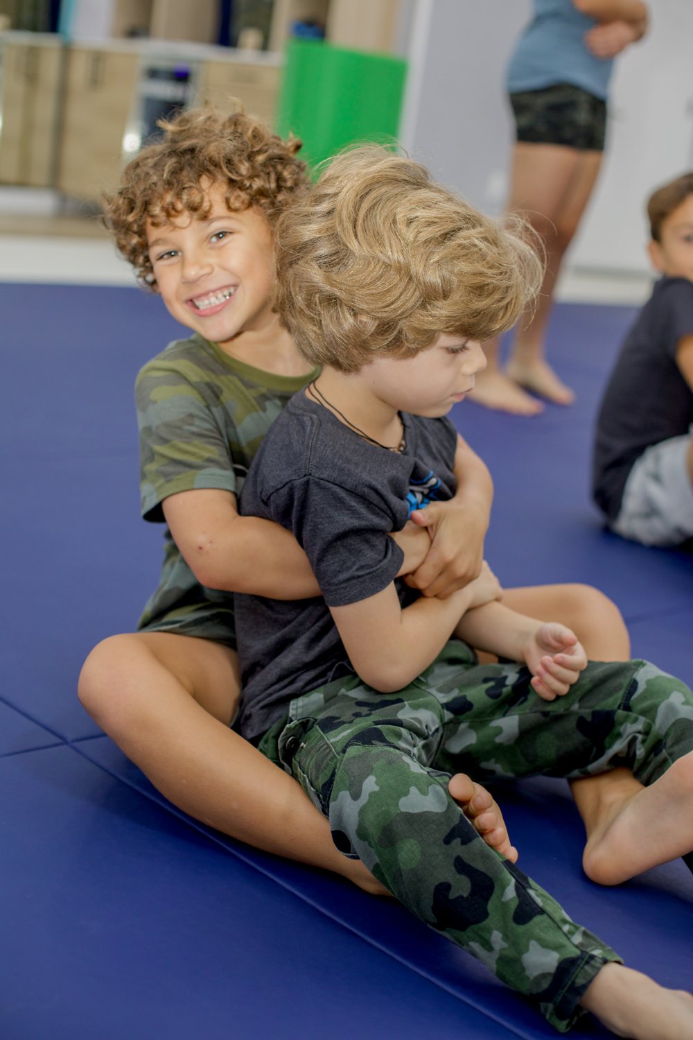 Two boys laughing on the mat during class