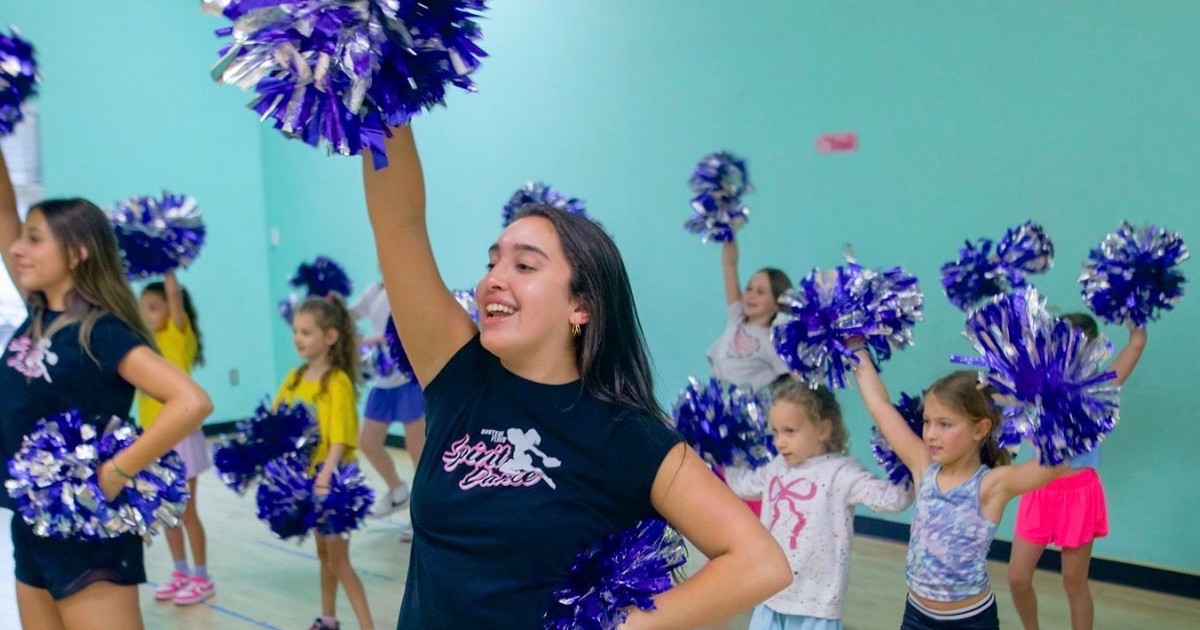 A Spirit Dance coach and students with pom-poms