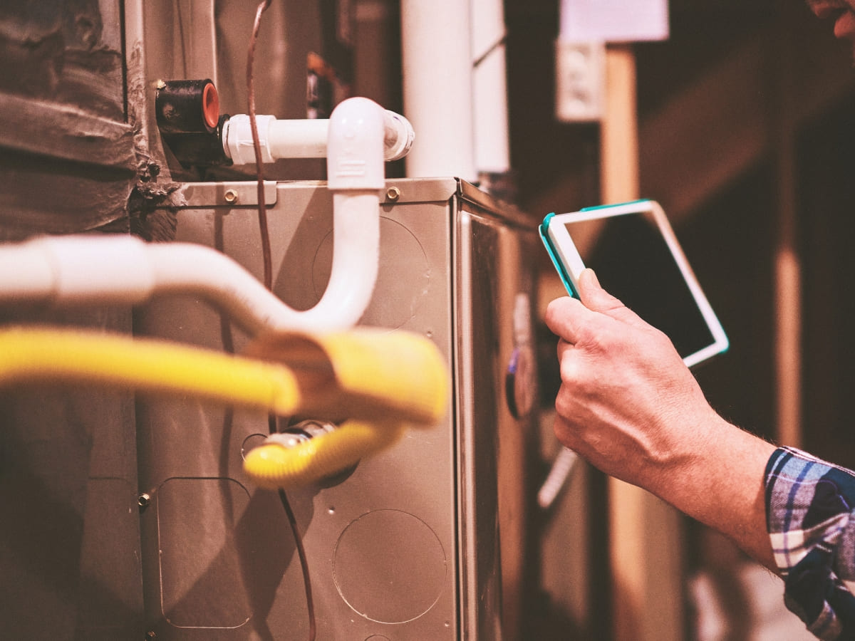 Technician performing a furnace checkup with a tablet, ensuring proper operation of a home heating system in Medford.