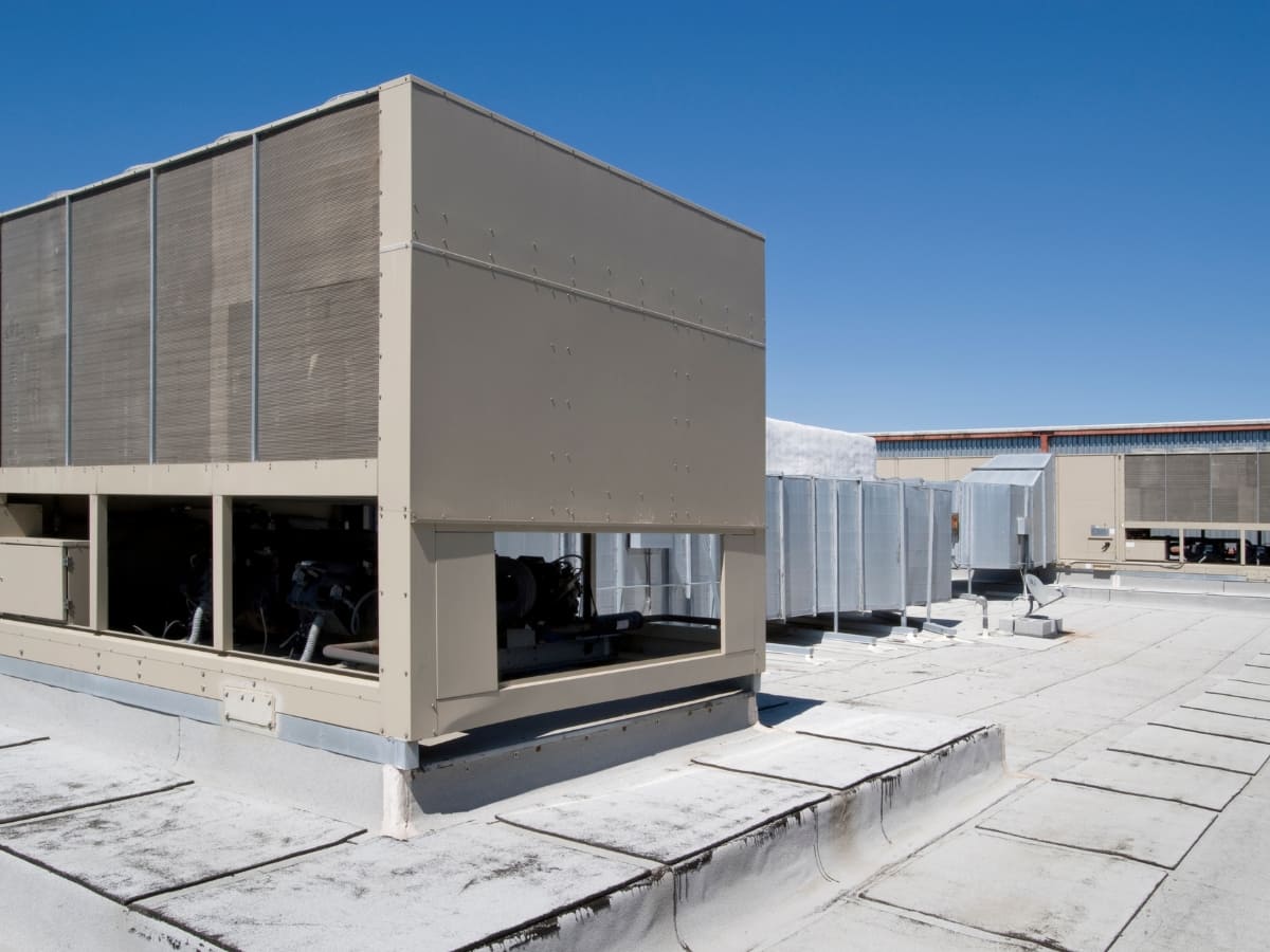 Large commercial rooftop air conditioning units installed on a flat roof, under a clear blue sky