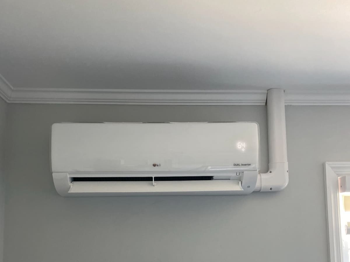 A wall-mounted LG dual inverter air conditioning unit with a visible temperature display, installed in a home interior.