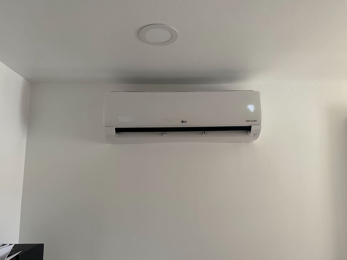 A wall-mounted LG dual inverter air conditioning unit in a minimalist, clean interior space.