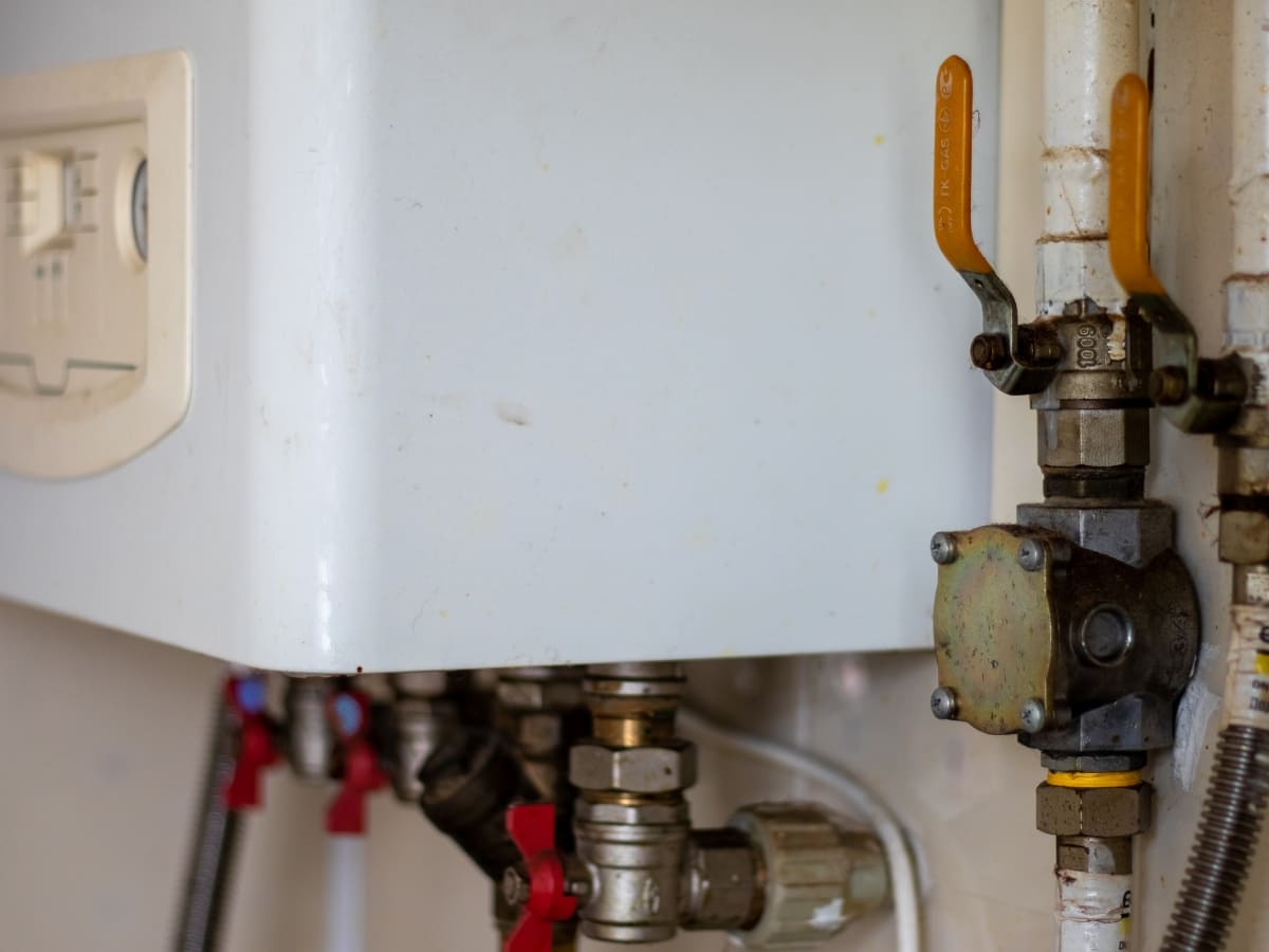 Close-up of a boiler system with various pipes and valves connected, displaying the intricate plumbing configuration.