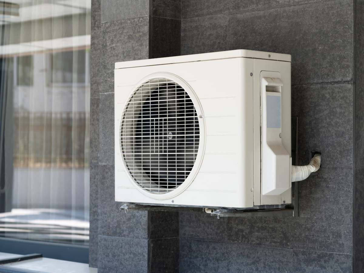 An outdoor air conditioning unit mounted on the wall of a building with a sleek, modern design.