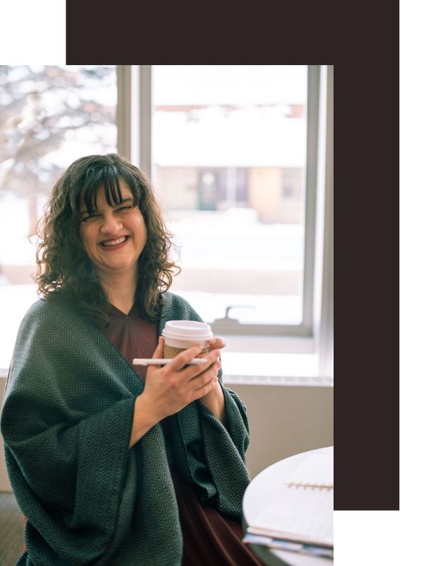 Lauren holding a coffee and pen and laughing
