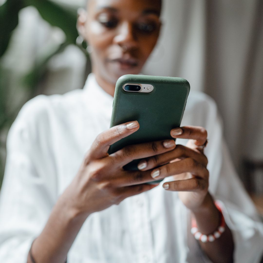 Woman (blurred in background) looking at phone (foreground)