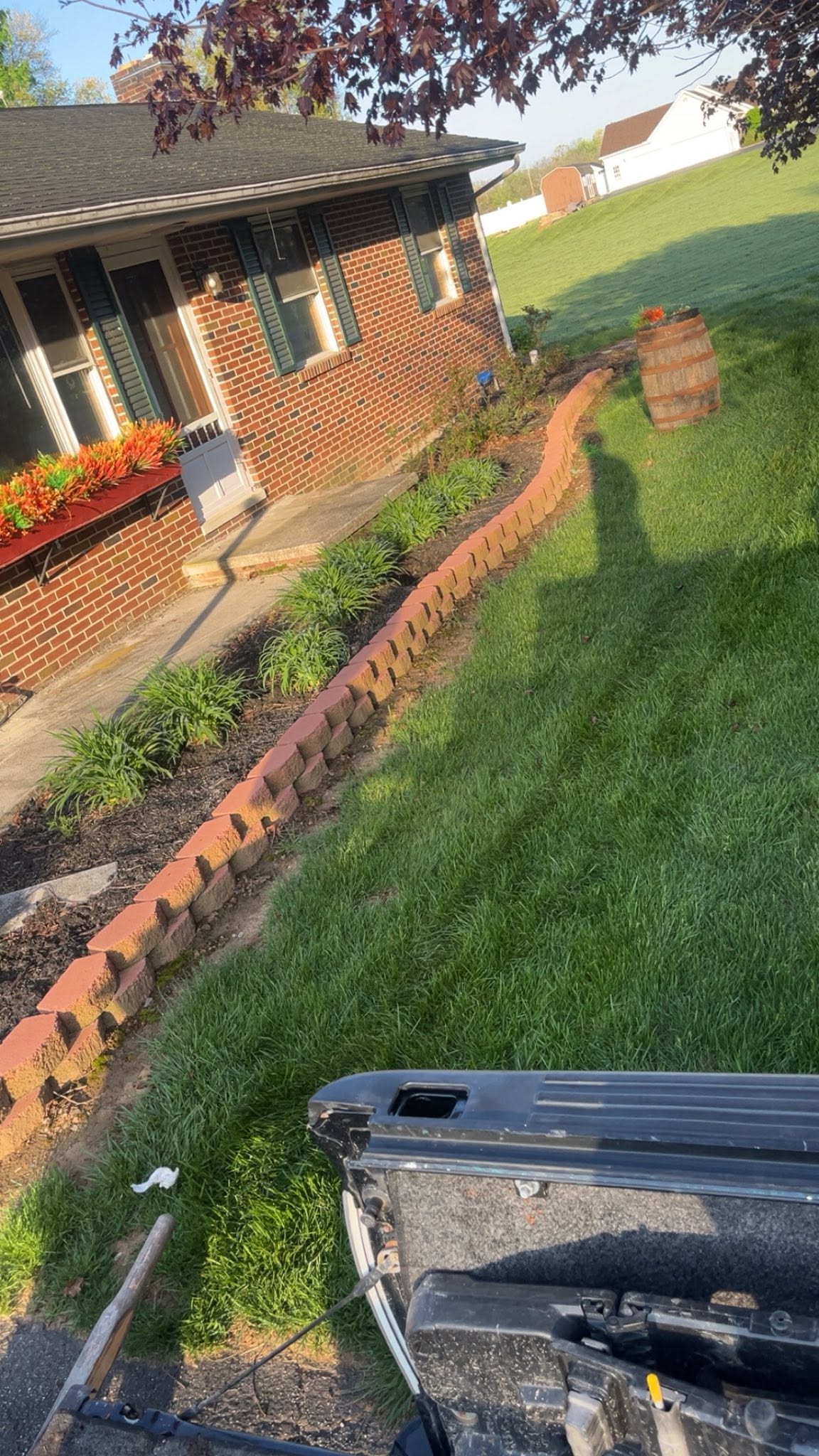 Edged garden bed with a block border and trimmed lawn at a brick home in Carroll County, MD