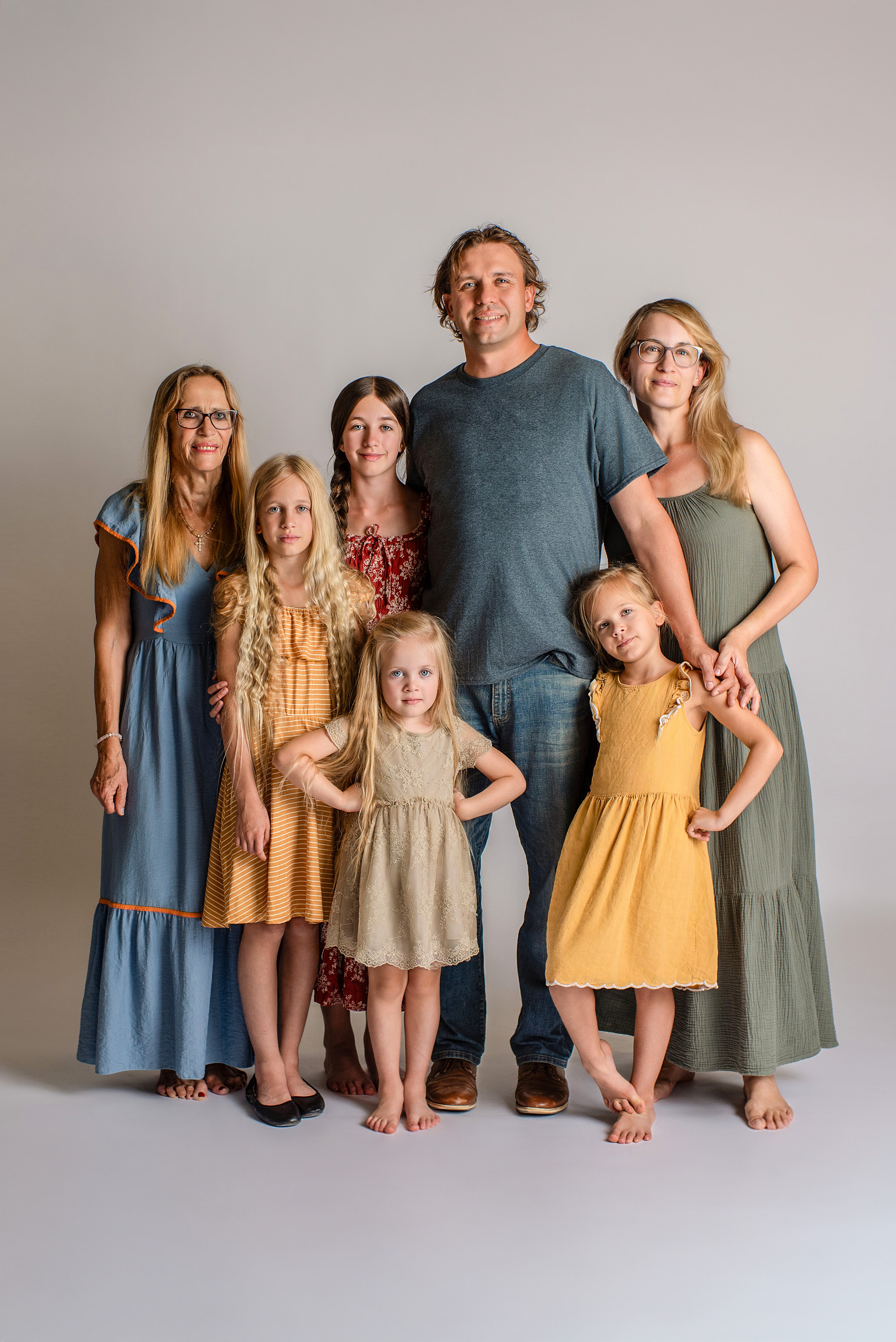 Large family photo session in studio with parents, 4 girls and grandmother in bright colors.