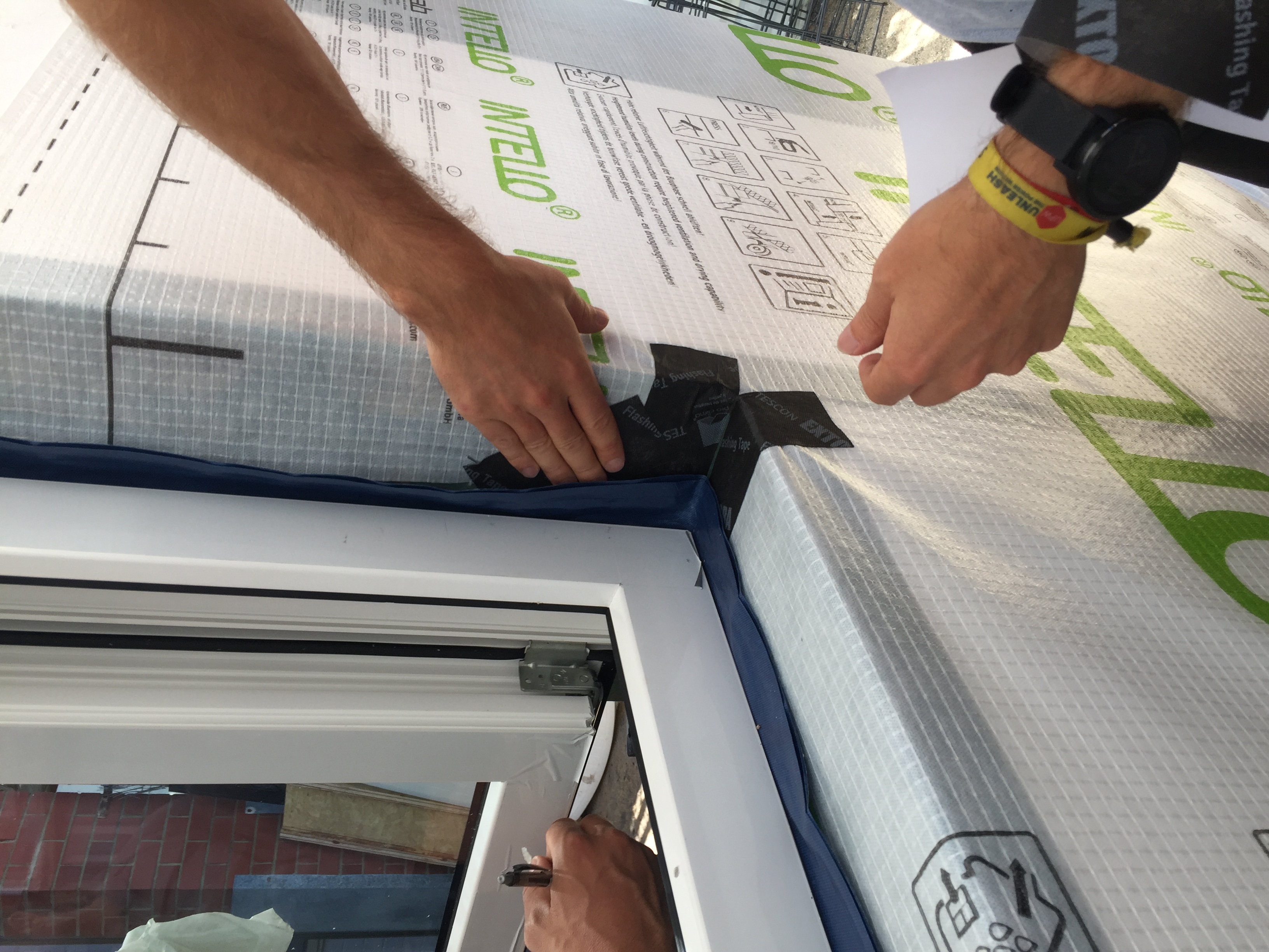Airtightness membrane being installed and taped at a window reveal.
