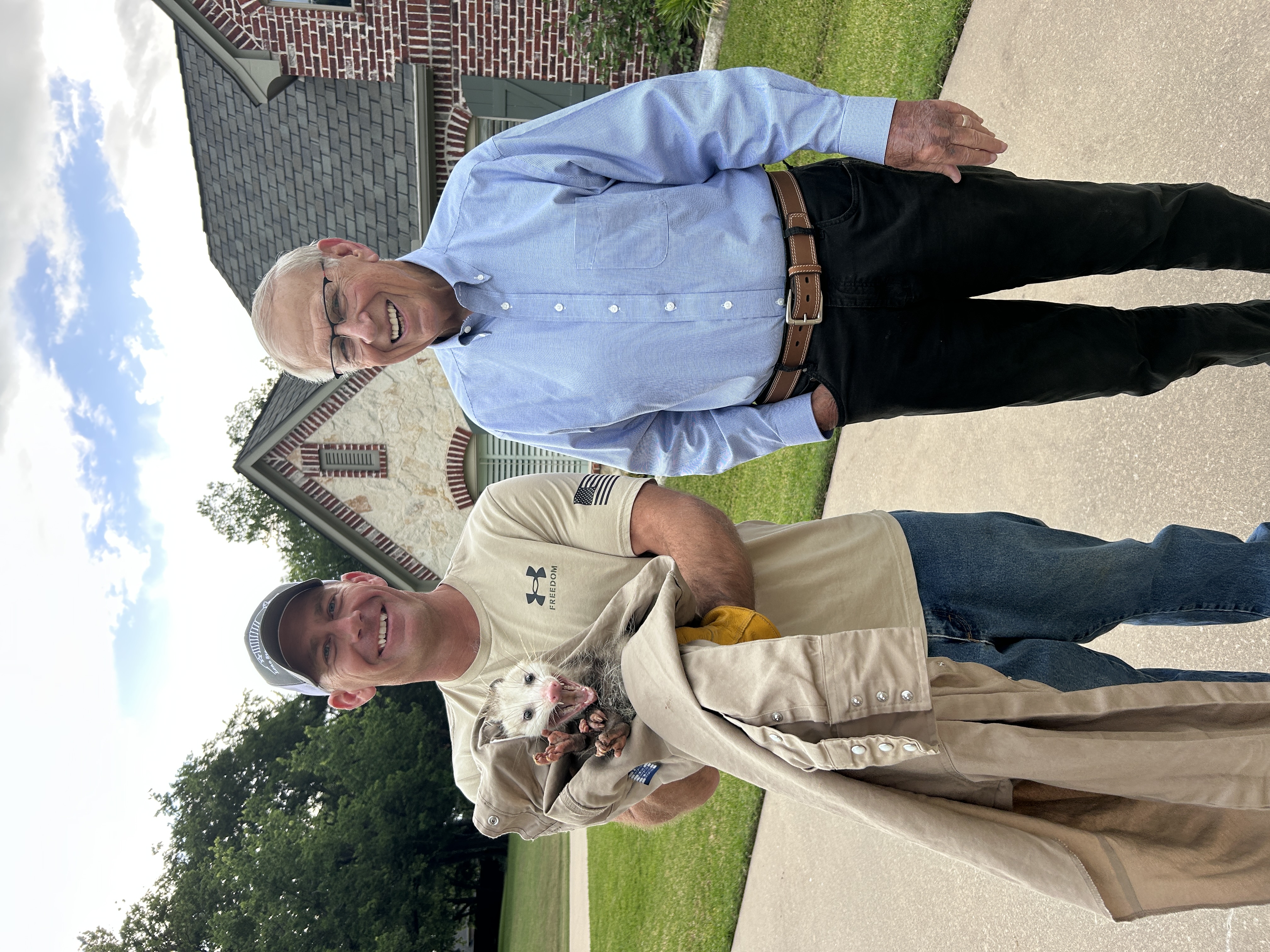 Lone Star Wildlife Solutions technician with captured opossum after successful removal from residential property