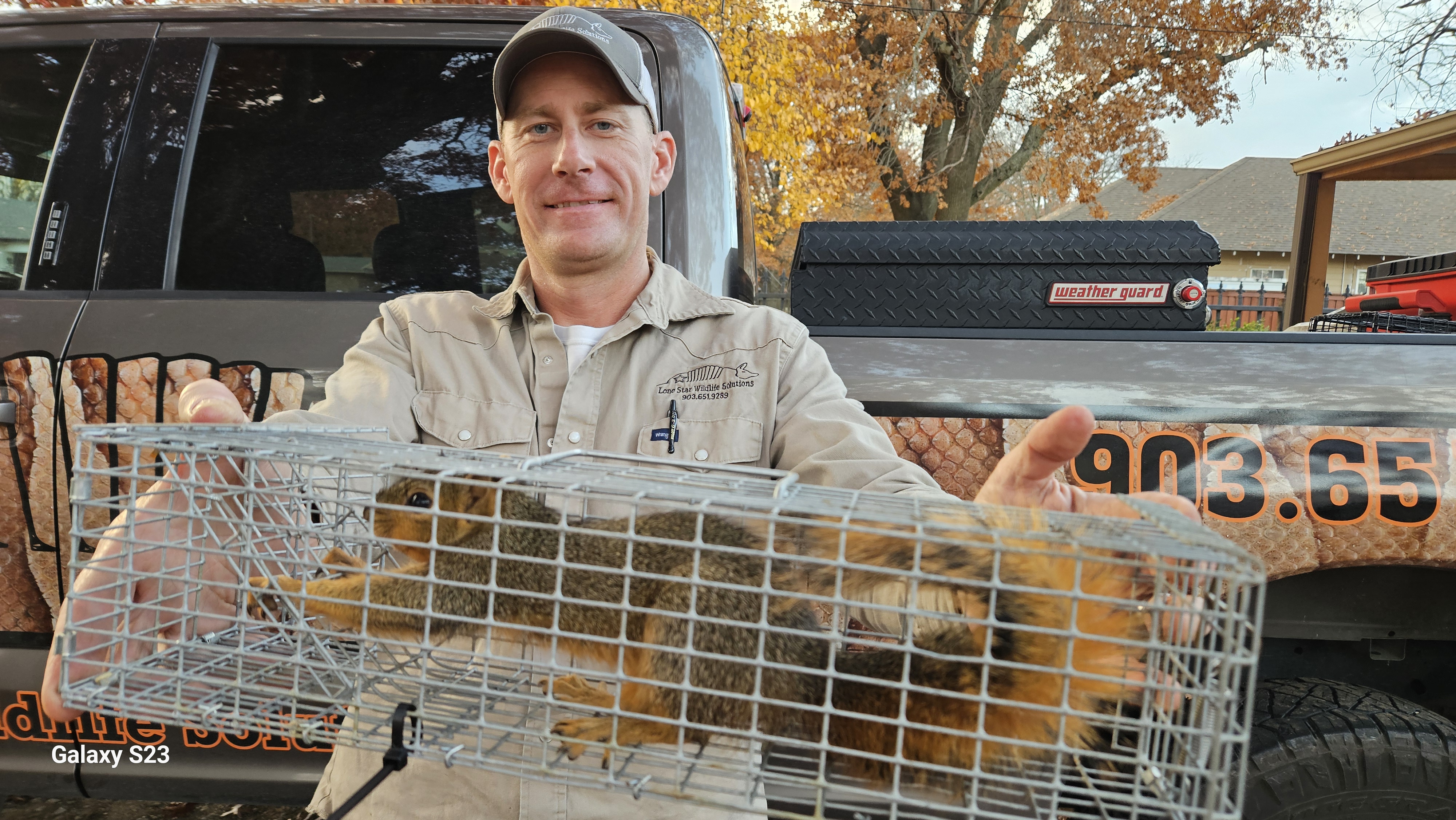 Lone Star Wildlife Solutions technician with captured squirrel after successful removal from residential property