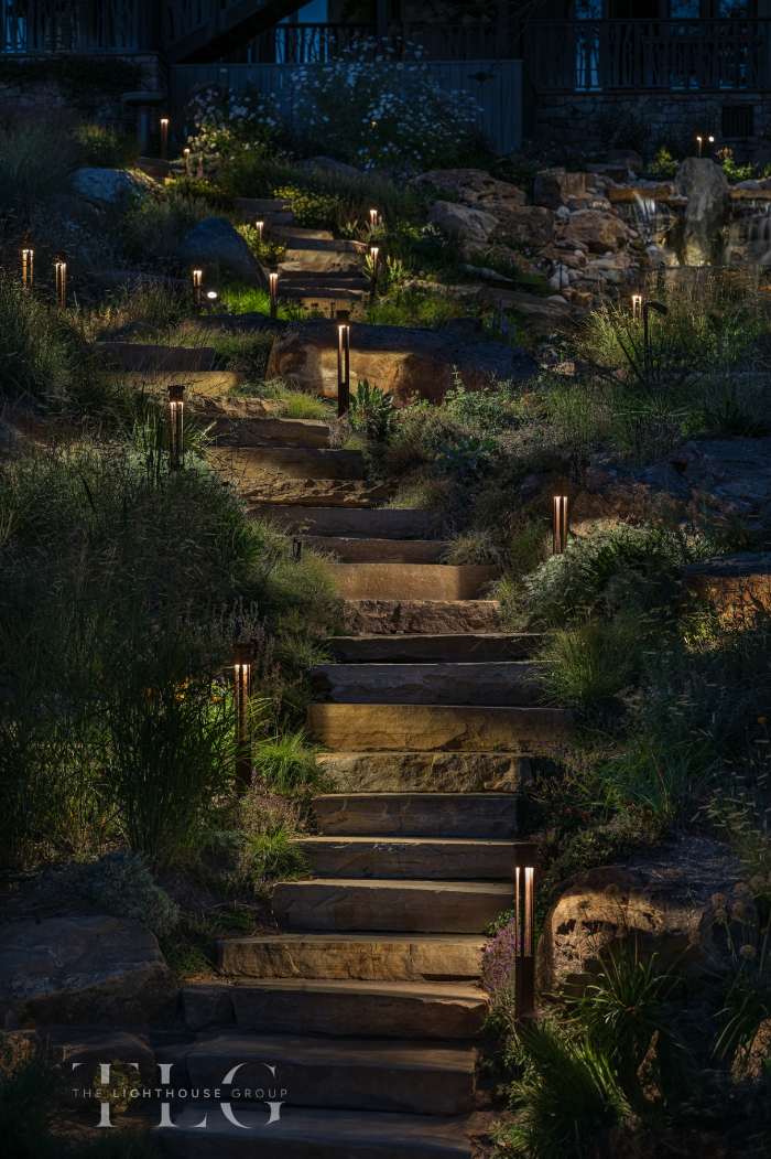 Lit staircase and pathway through a landscape