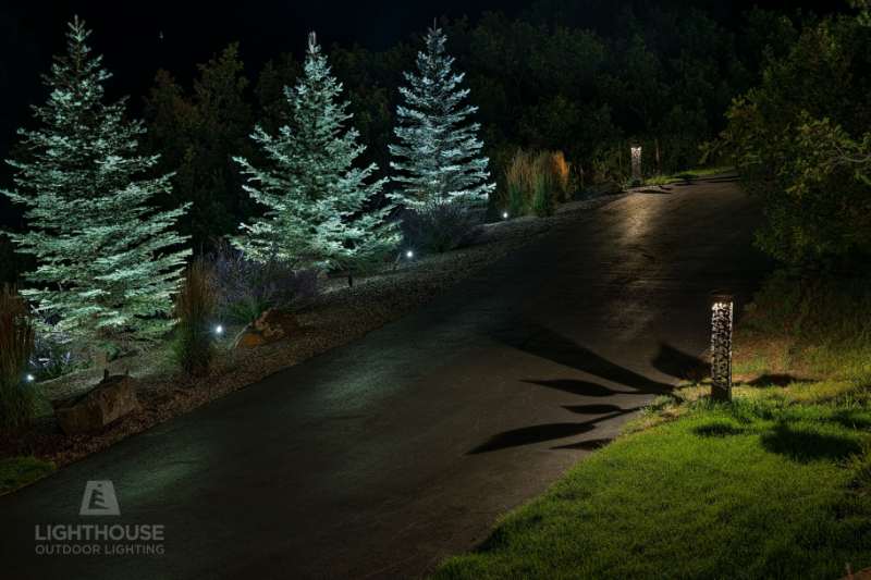 Blue spruce and home exterior lit at night by Lighthouse