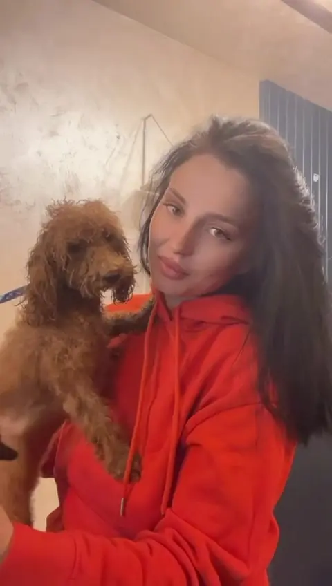 Natalia ține în brațe un pudel toy roșcat, după grooming