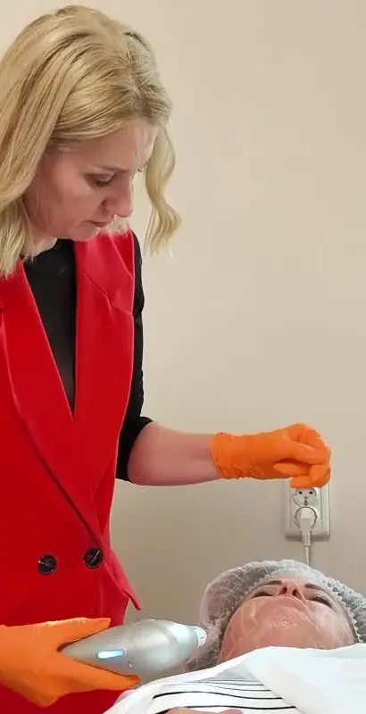 Ramona Vermeșan face un tratament facial cu aparat unei cliente întinse pe pat