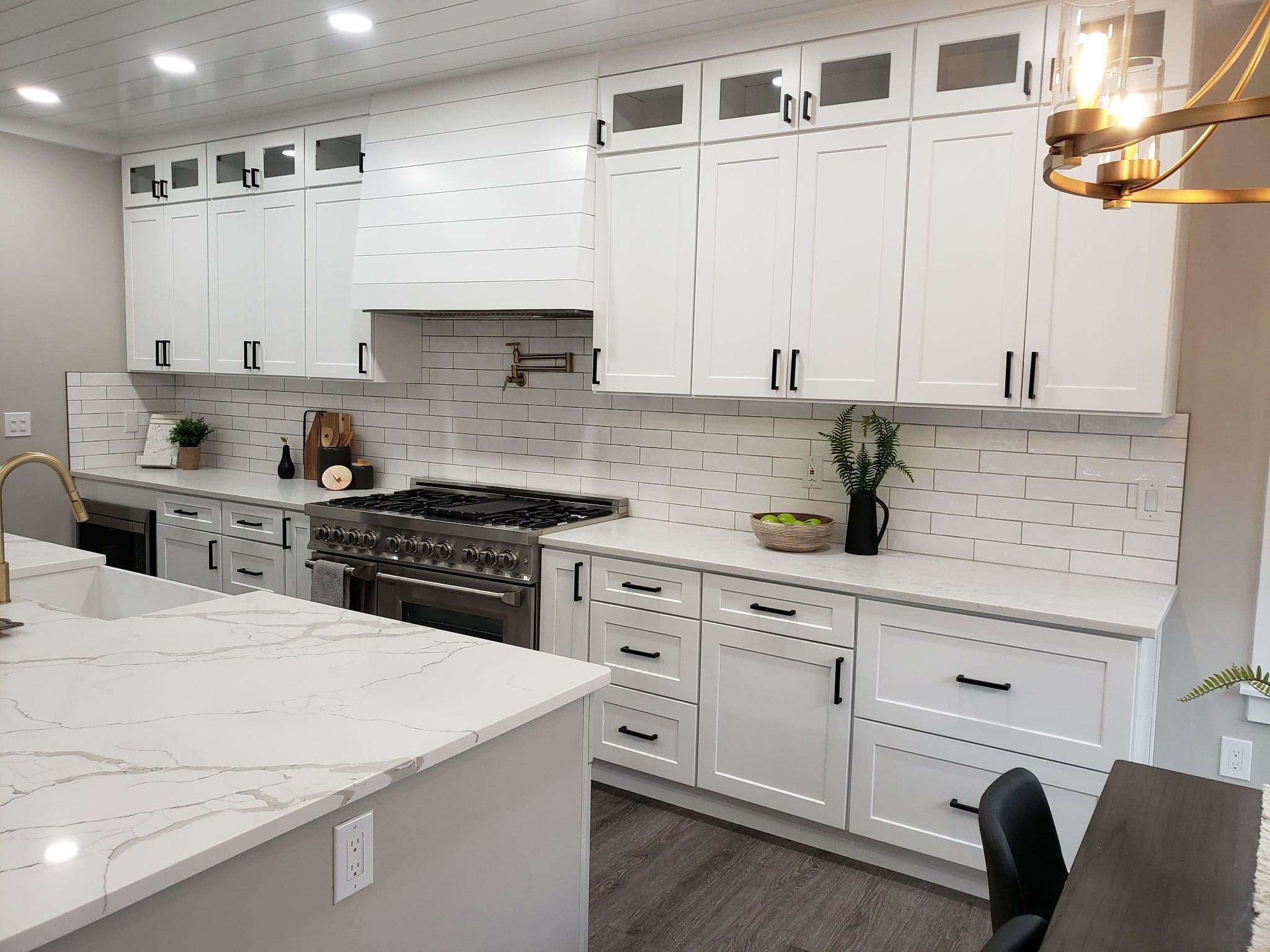 Brand new kitchen with custom white cabinets set against a white tile backsplash