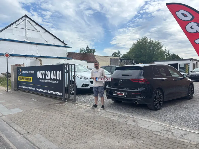 Klant van Automotive Belgium met het bordje verkocht bij zijn zwarte Volkswagen Golf GTI