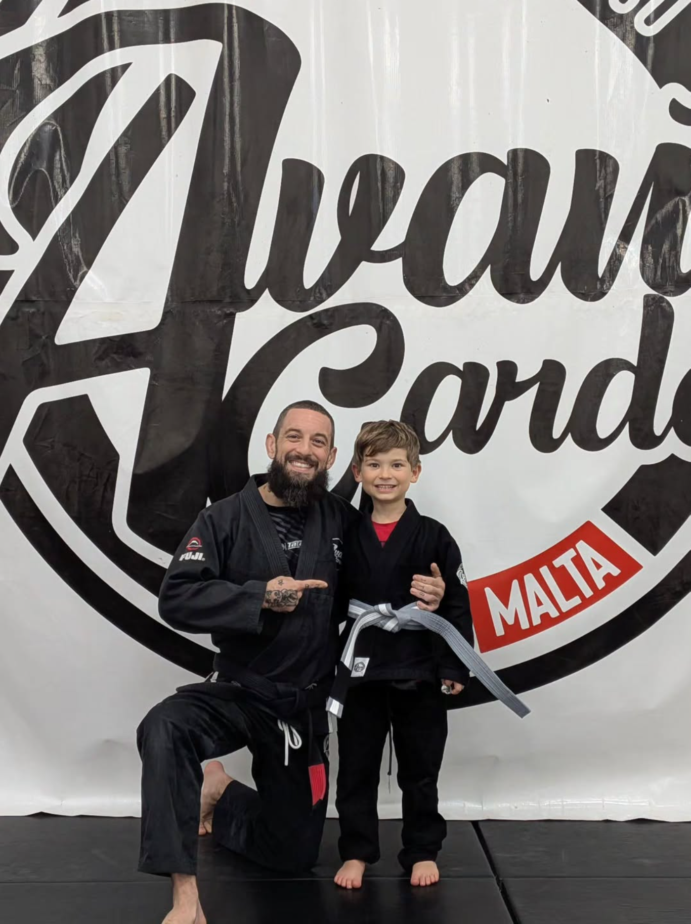 Coach grading a child with a new belt at Avant-Garde BJJ