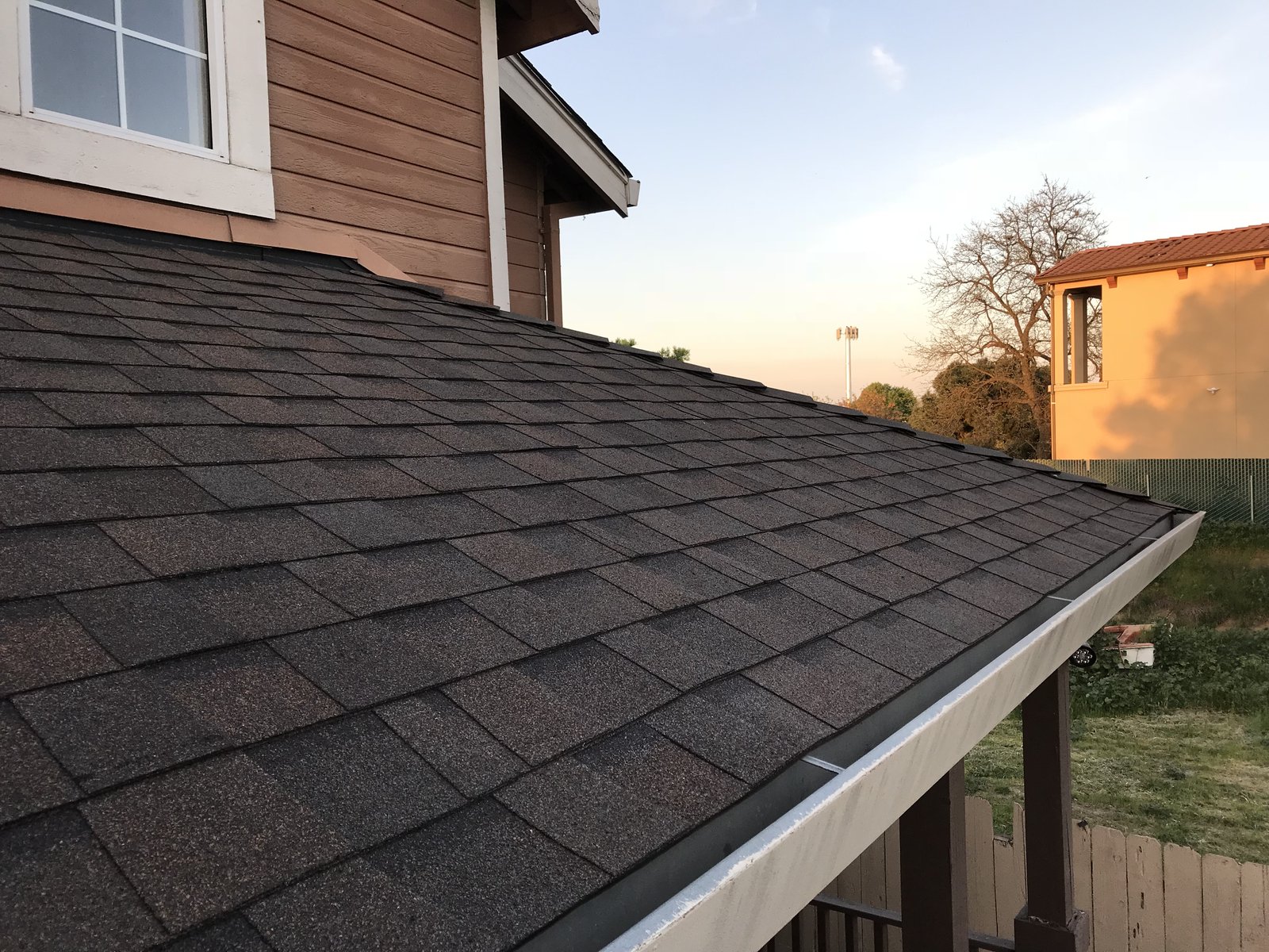 New architectural shingles meeting a white gutter and drip edge