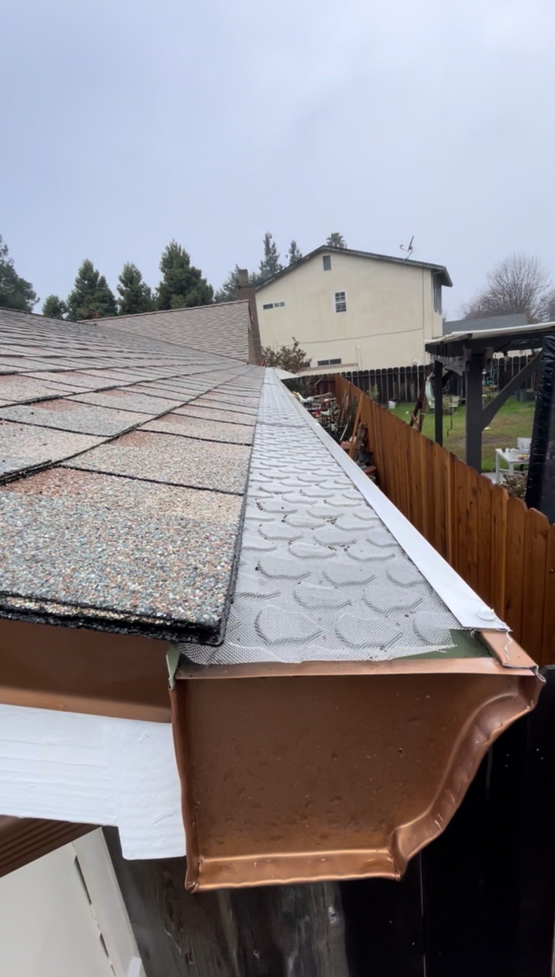 Close view of micro-mesh gutter guard under asphalt shingles