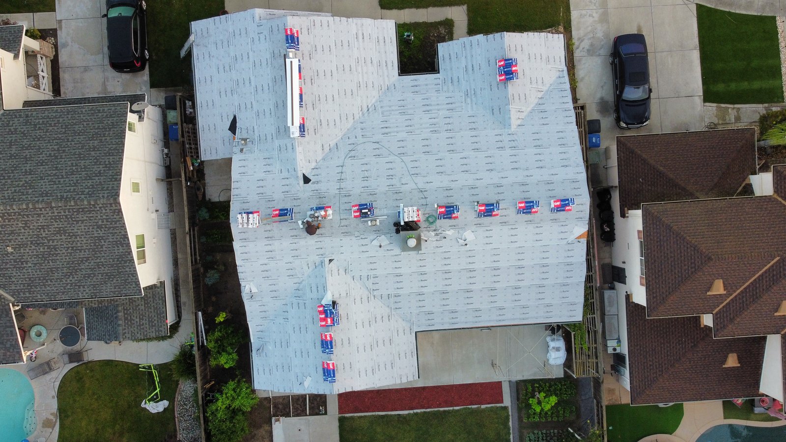 Aerial view of a Modesto-area home with synthetic underlayment and staged GAF shingle bundles