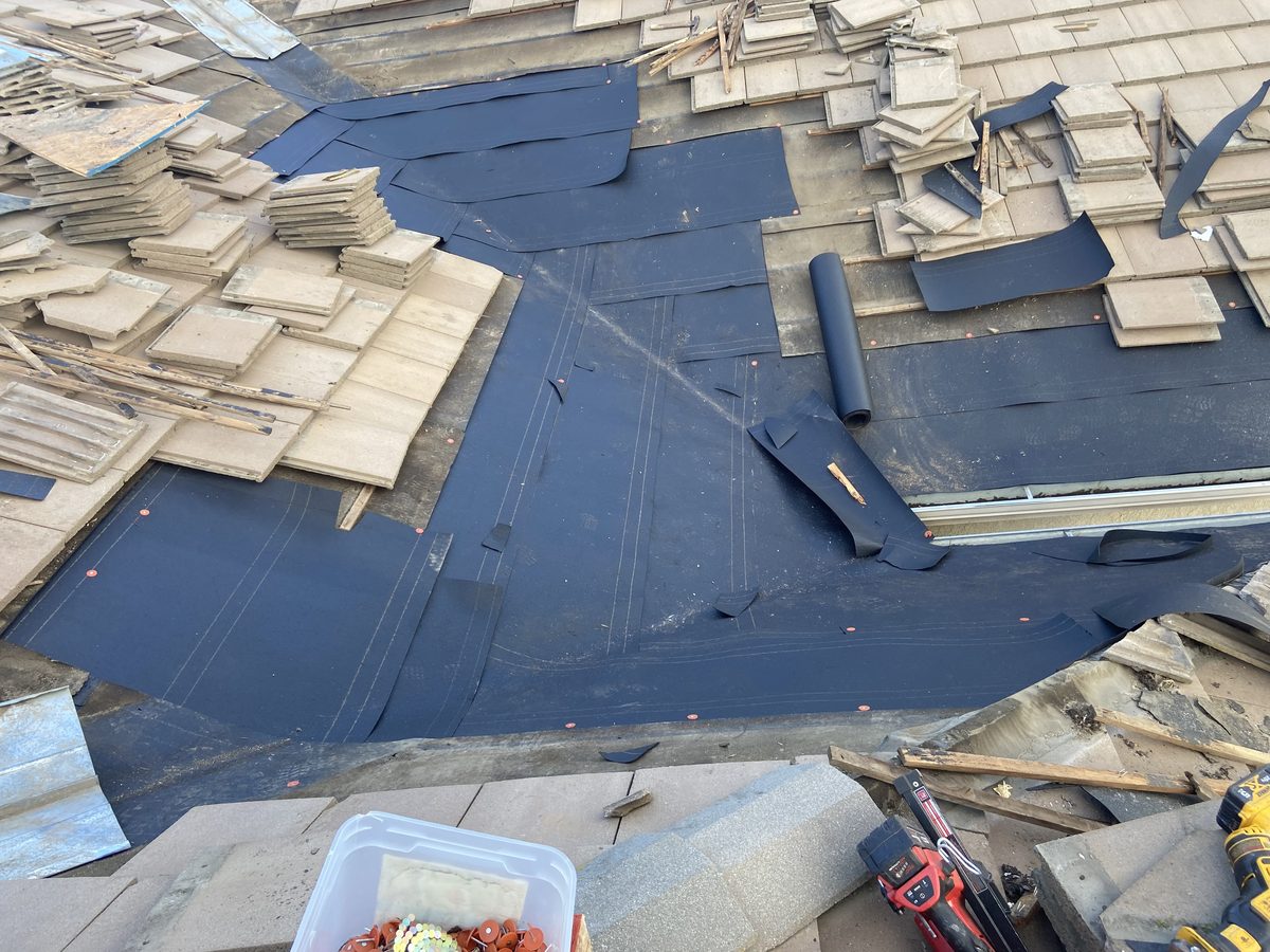 New black underlayment secured with orange plastic cap nails in a Ripon tile valley before tiles return