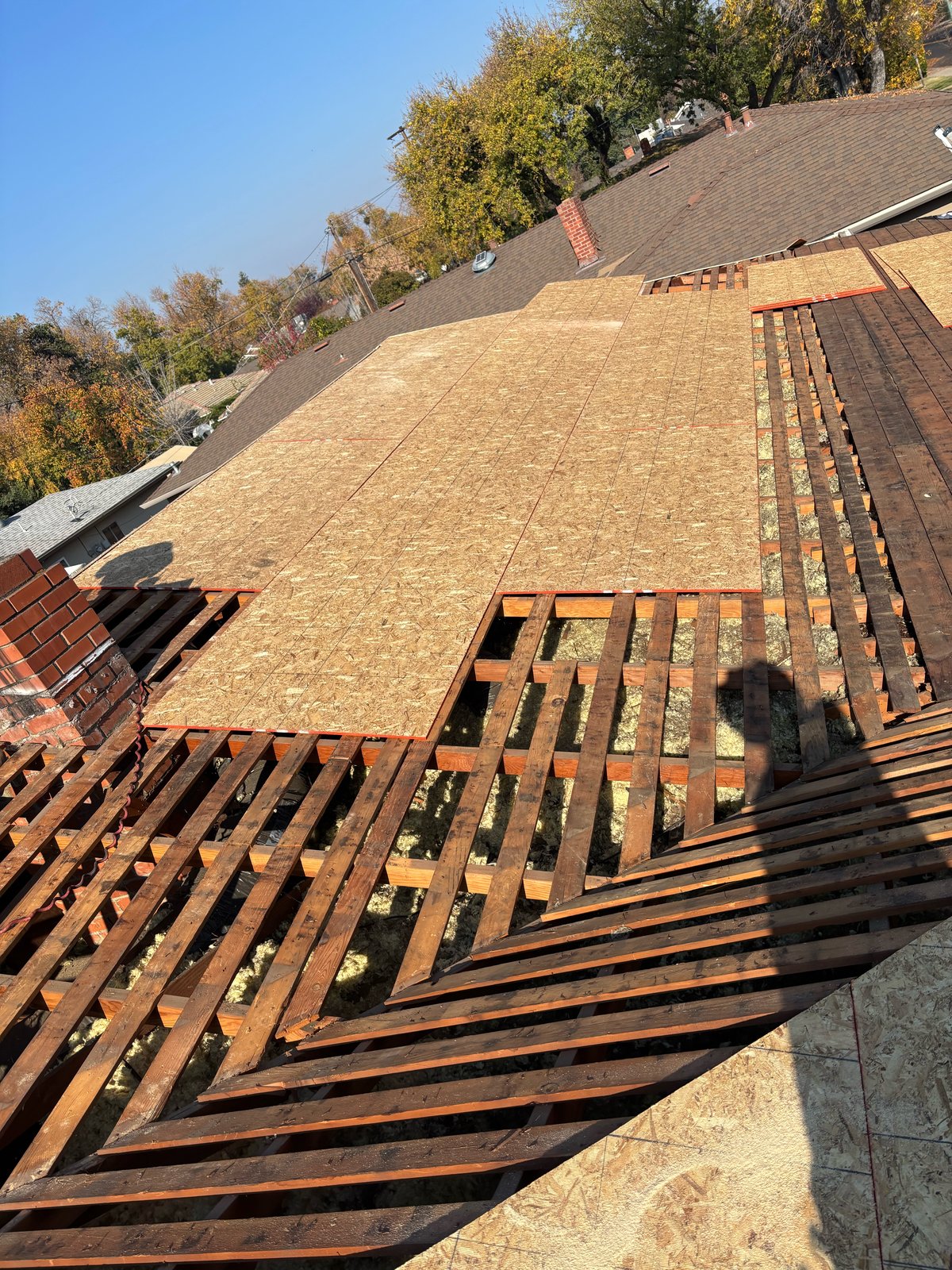 Fresh OSB roof decking installed over older skip sheathing and rafters on a Turlock residential roof replacement