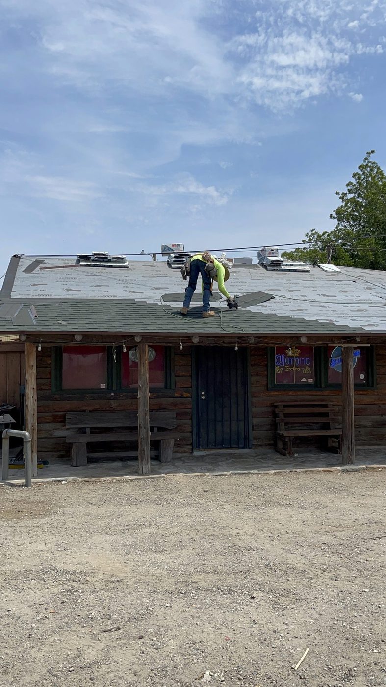Roofer nailing architectural shingle courses at the eave over GAF FeltBuster synthetic underlayment on a Modesto-area job