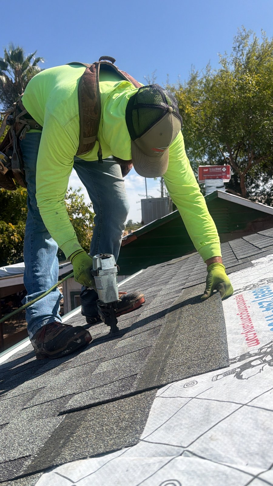 Legend Roofing Company Inc crew member fastening architectural shingles with a pneumatic nailer over Legend-branded underlayment