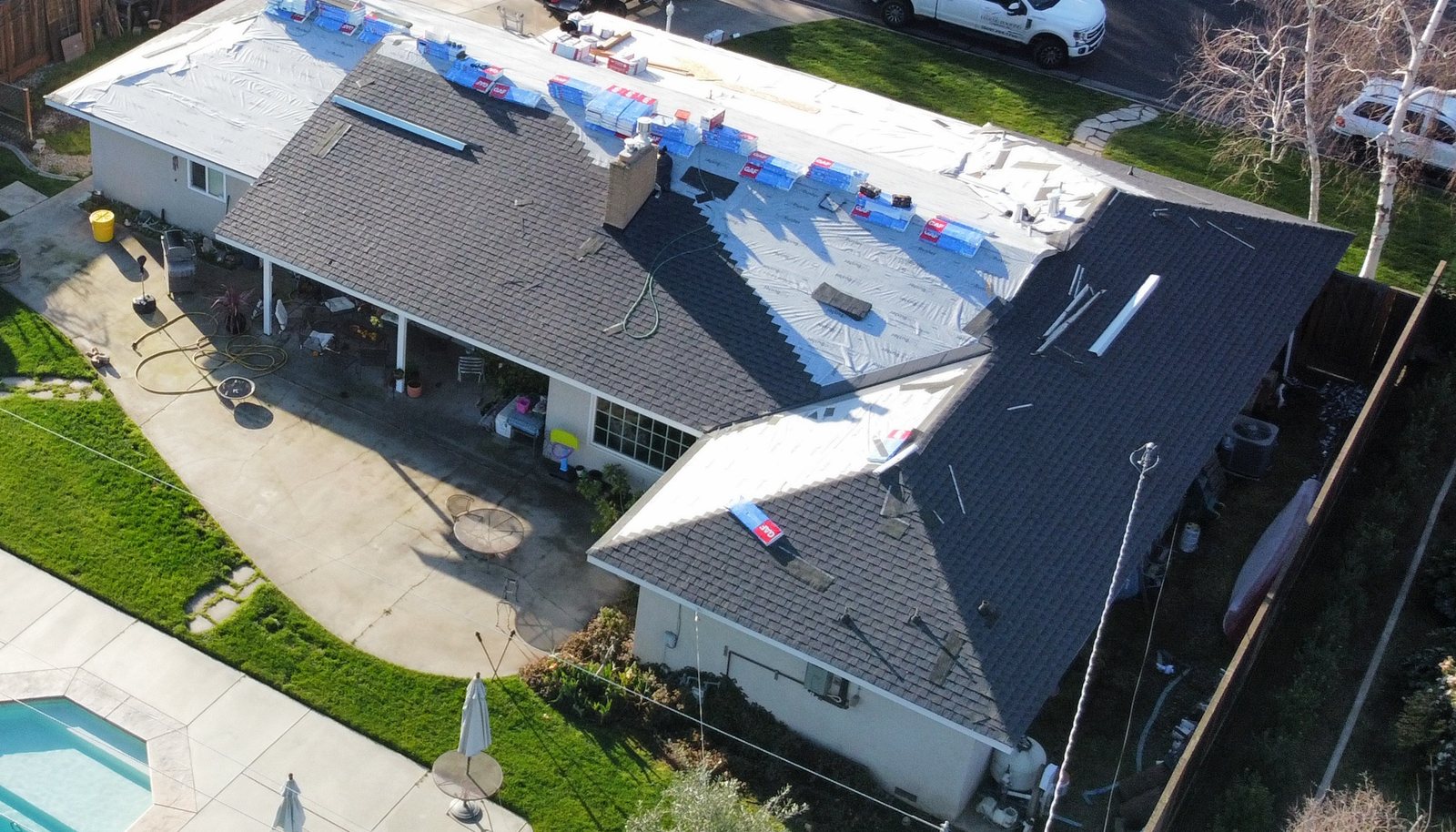 Modesto home partway through installation of GAF Timberline architectural shingles in Charcoal, with finished planes next to dried-in planes