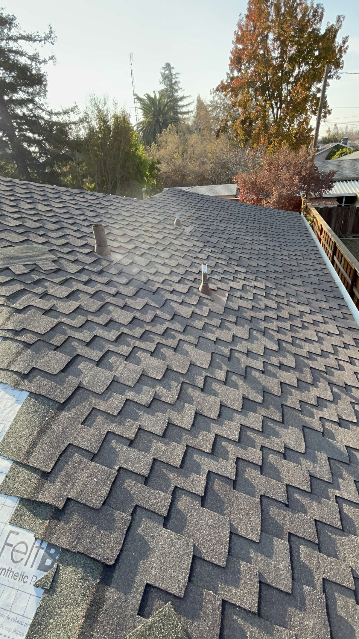Close-up of GAF Grand Sequoia designer shingles installed on a Modesto roof, showing the oversized, irregular tabs, flashed pipe vents and FeltBuster synthetic underlayment at the edge