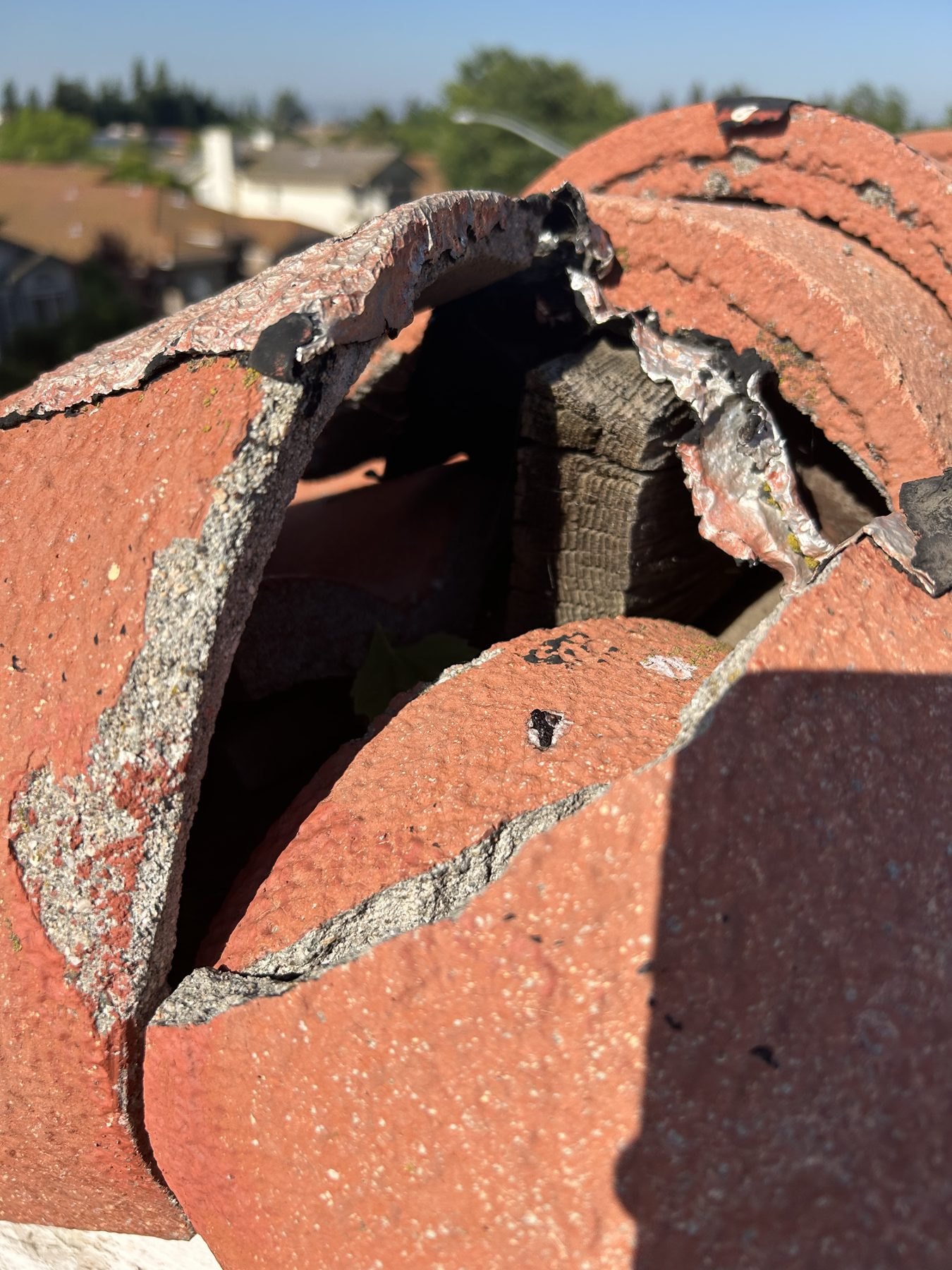 Close-up of broken and cracked clay ridge tiles leaving an opening on a tile roof