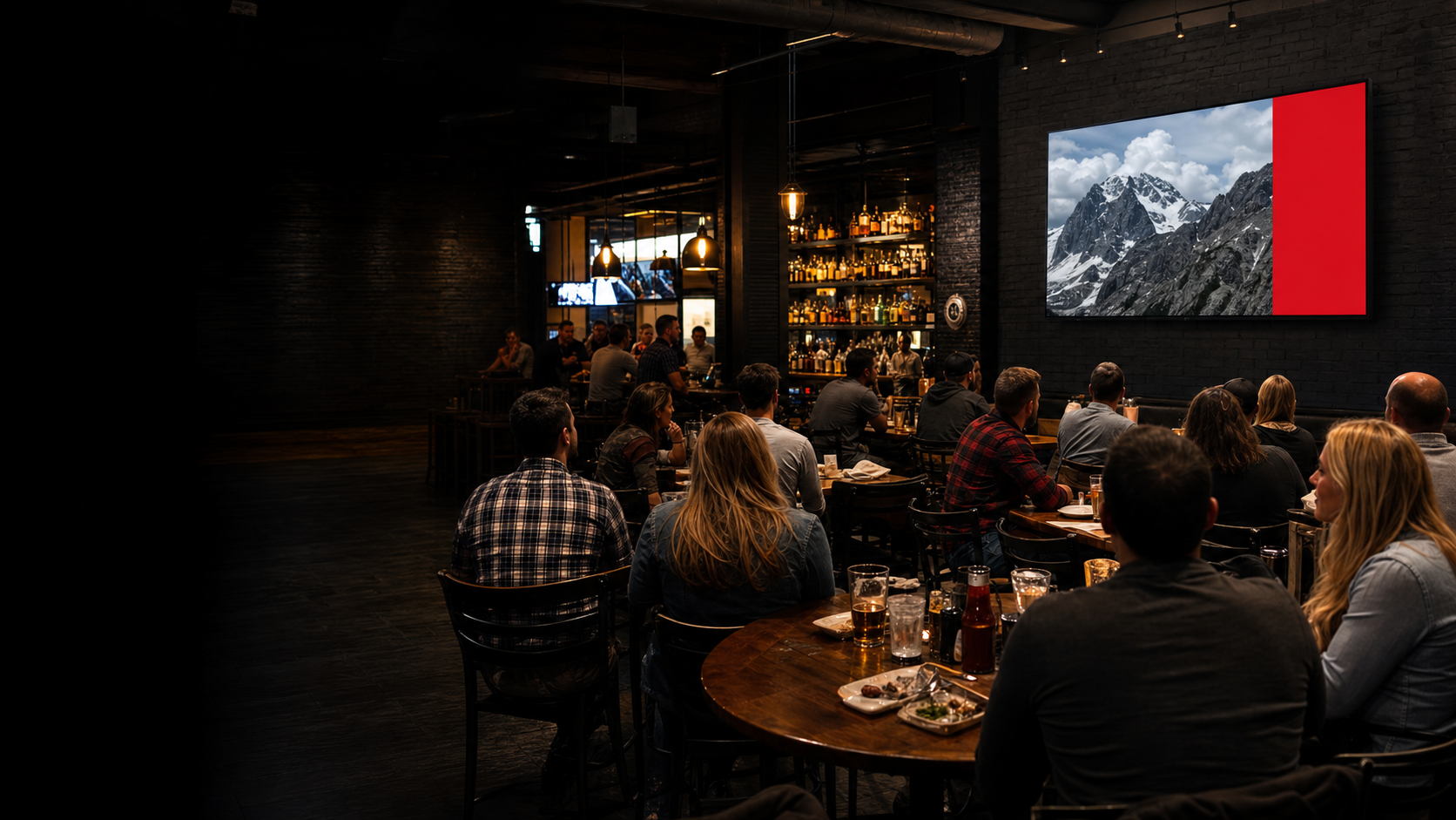 Customers watching an Adventure Media television inside a busy local bar and grill
