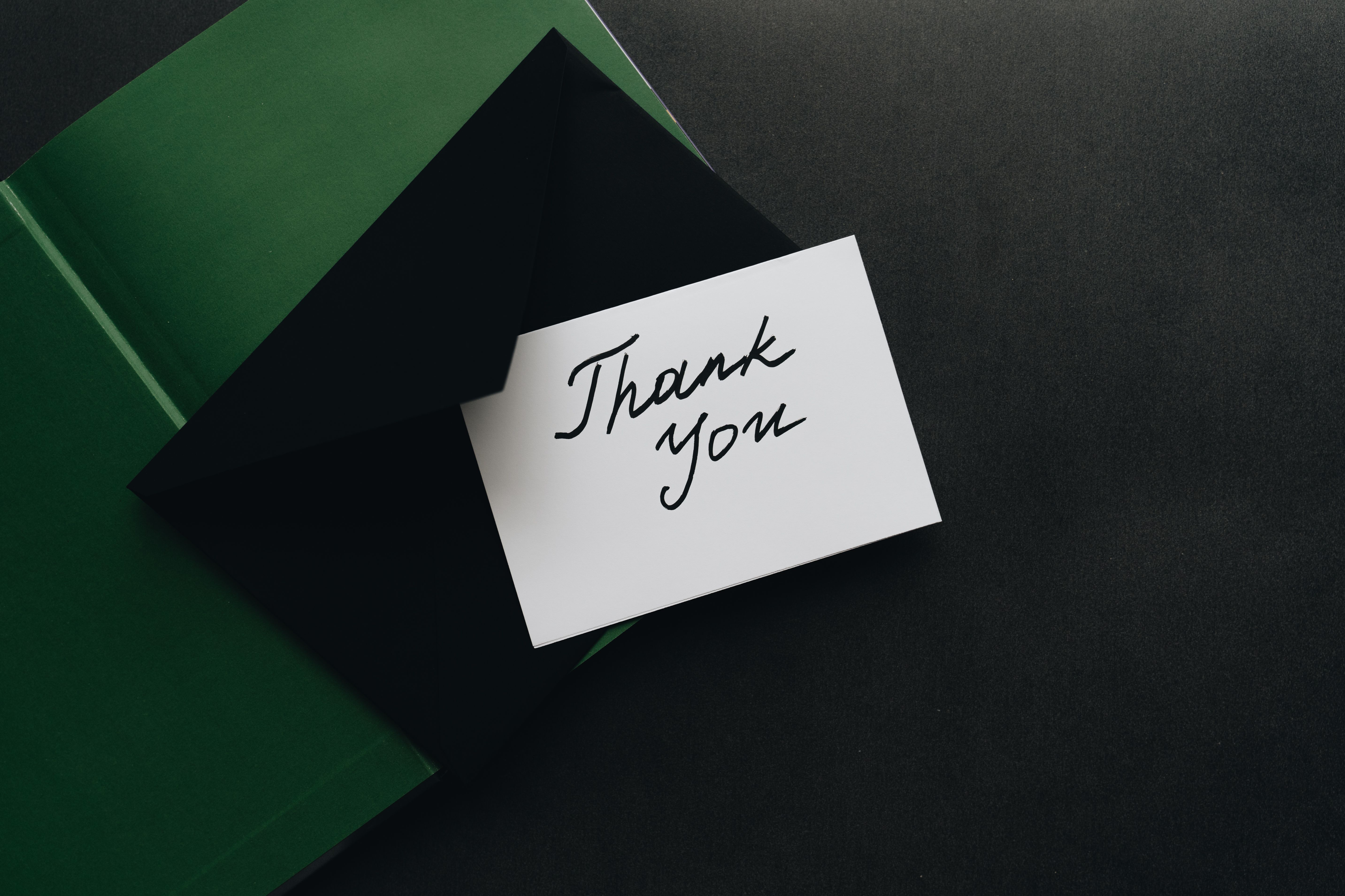 A handwritten thank-you card presented with a modern envelope