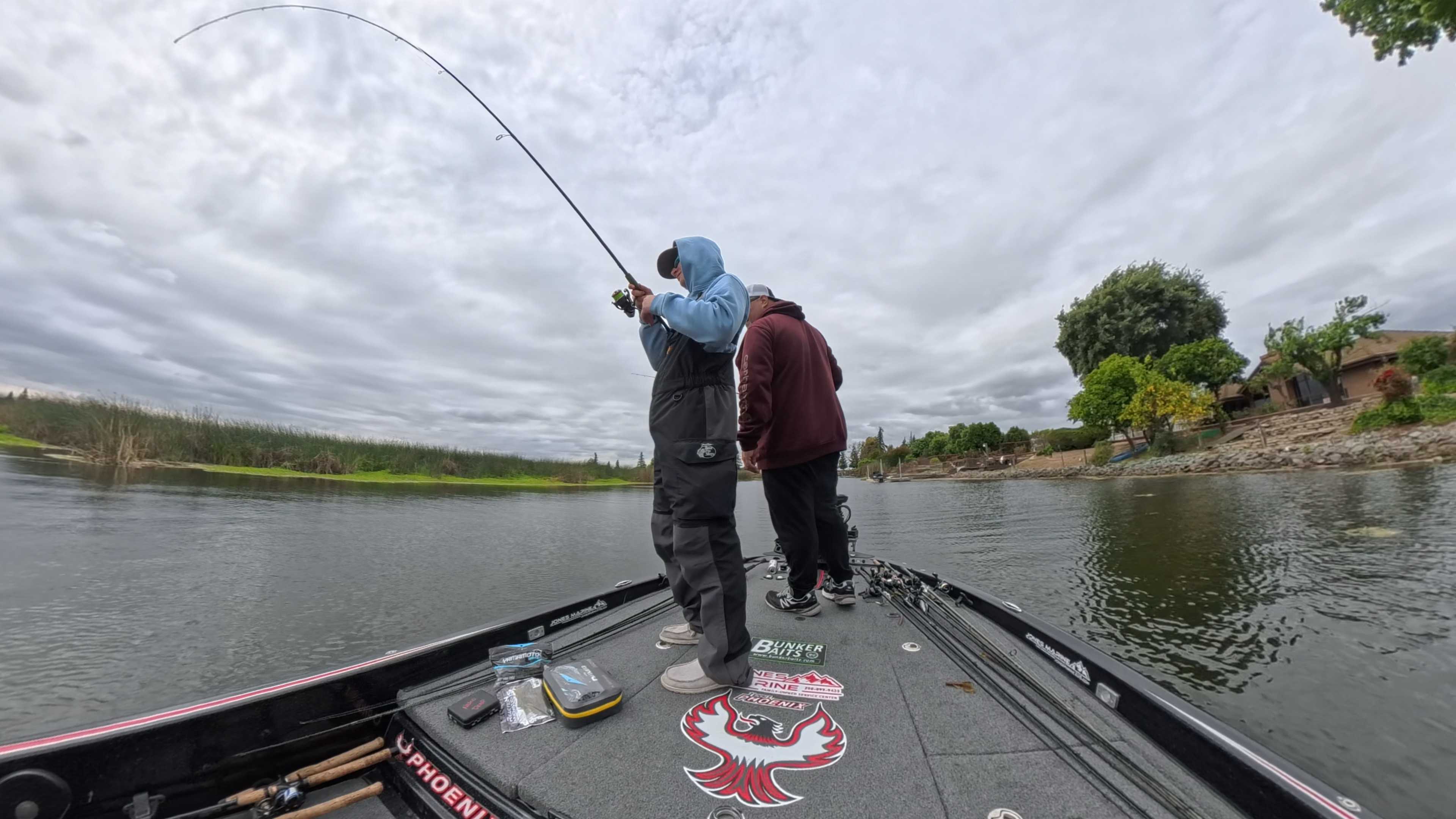 Carter fighting a bass from the front deck with Sam beside him