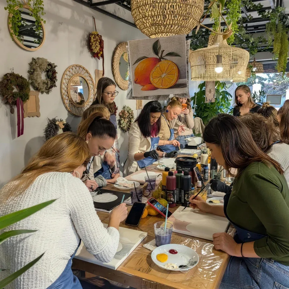Grup de prietene care pictează în relief la o masă lungă, la Melinda Art