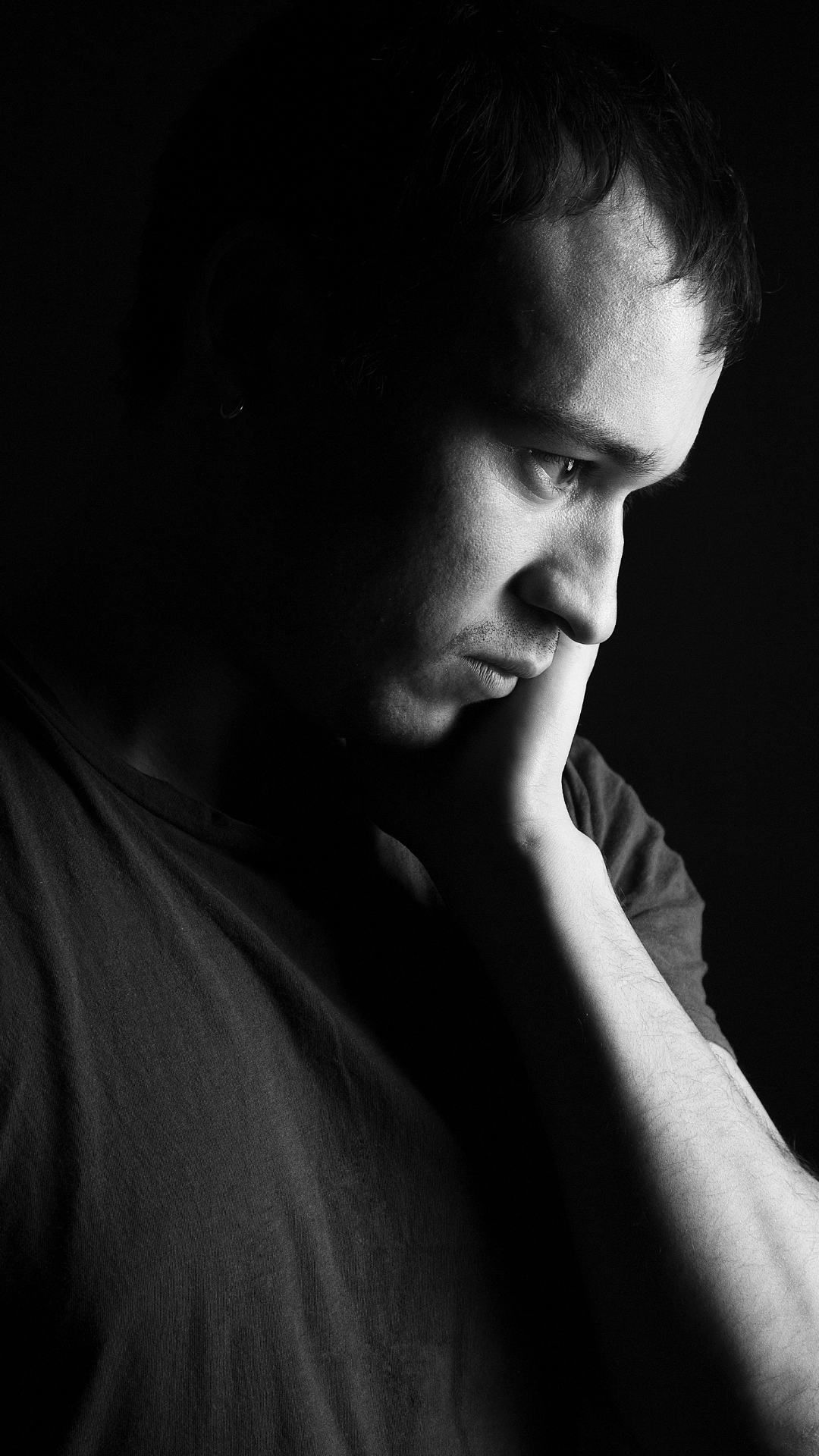 man sitting with a sad, emotionally exhausted expression.