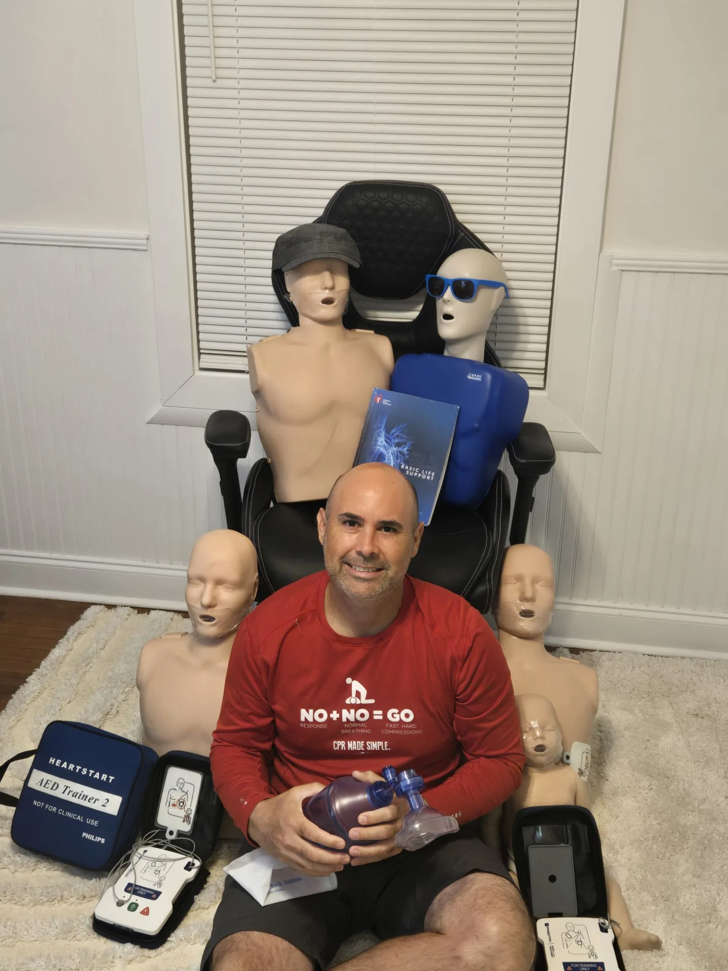 Alex with CPR mannequins, AED trainers and emergency-response training equipment