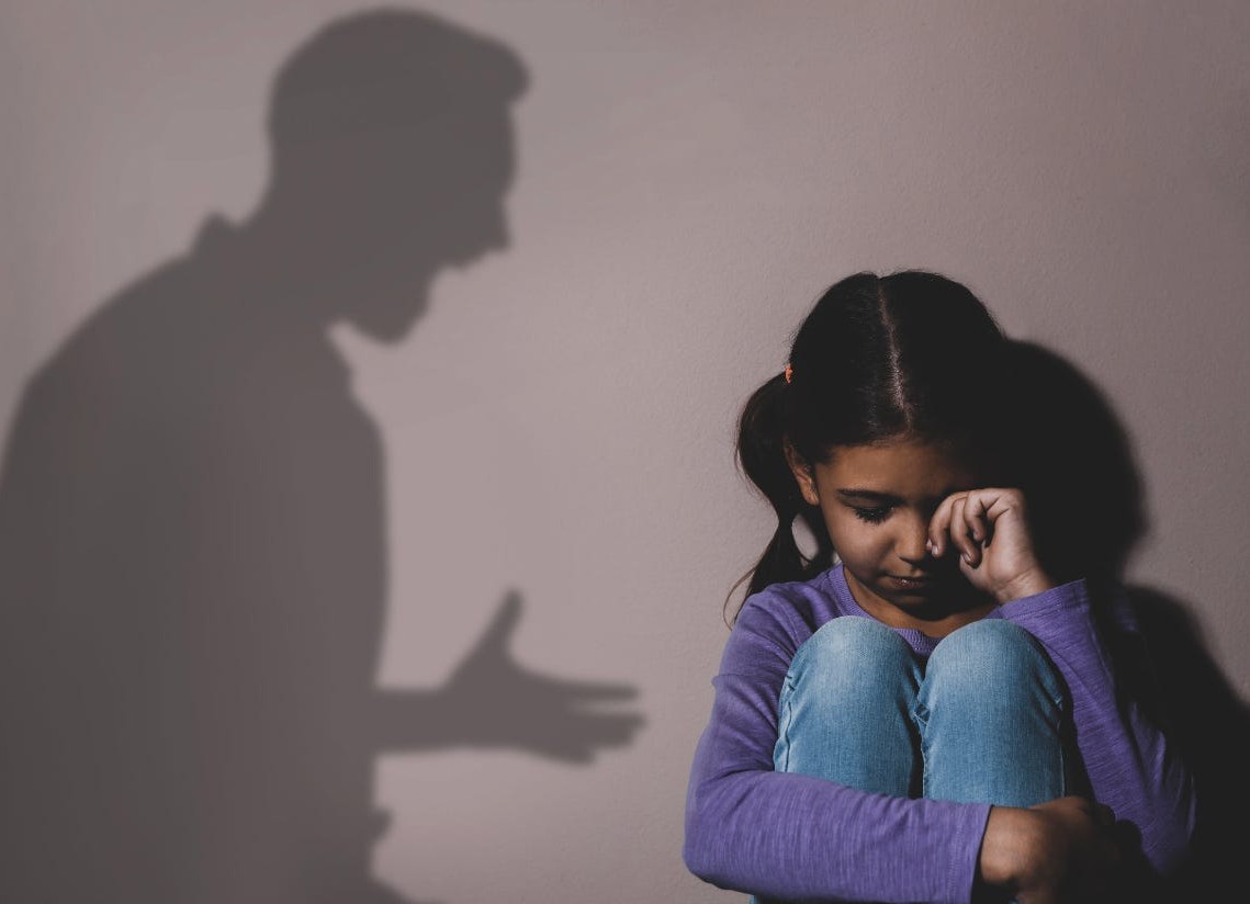 Distressed child with shadow of angry adult, symbolizing the impact of harsh discipline and the need for supportive, regulated environments for children. Distressed child with shadow of angry adult, symbolizing the impact of harsh discipline and the need for supportive, regulated environments for children.