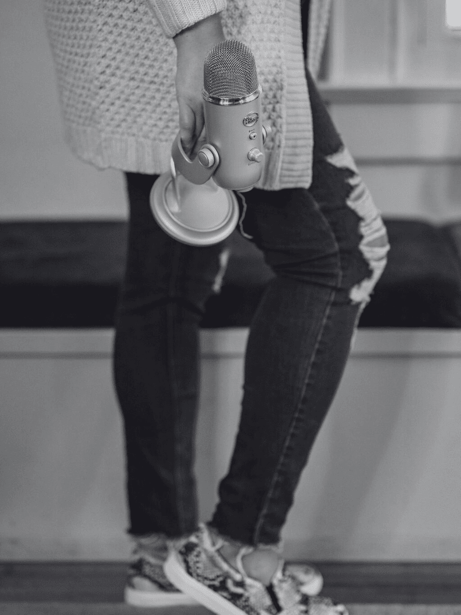 Podcast host recording at a microphone in a warm, styled studio