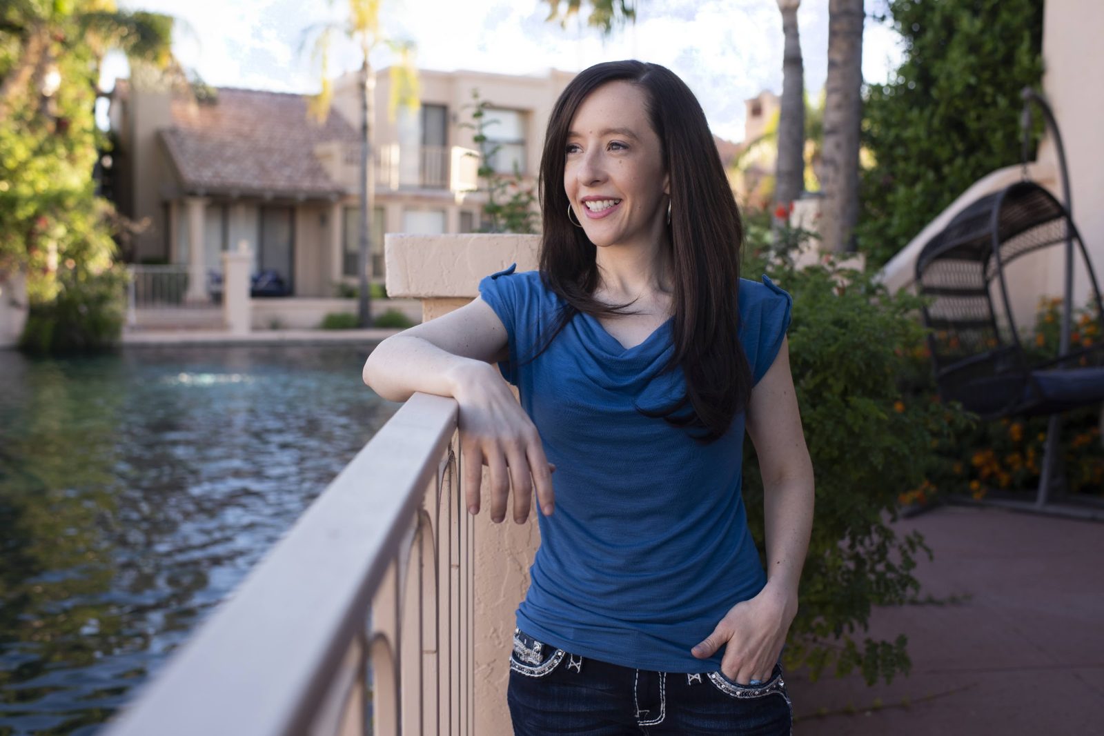 Mindie leaning on a railing beside a pond