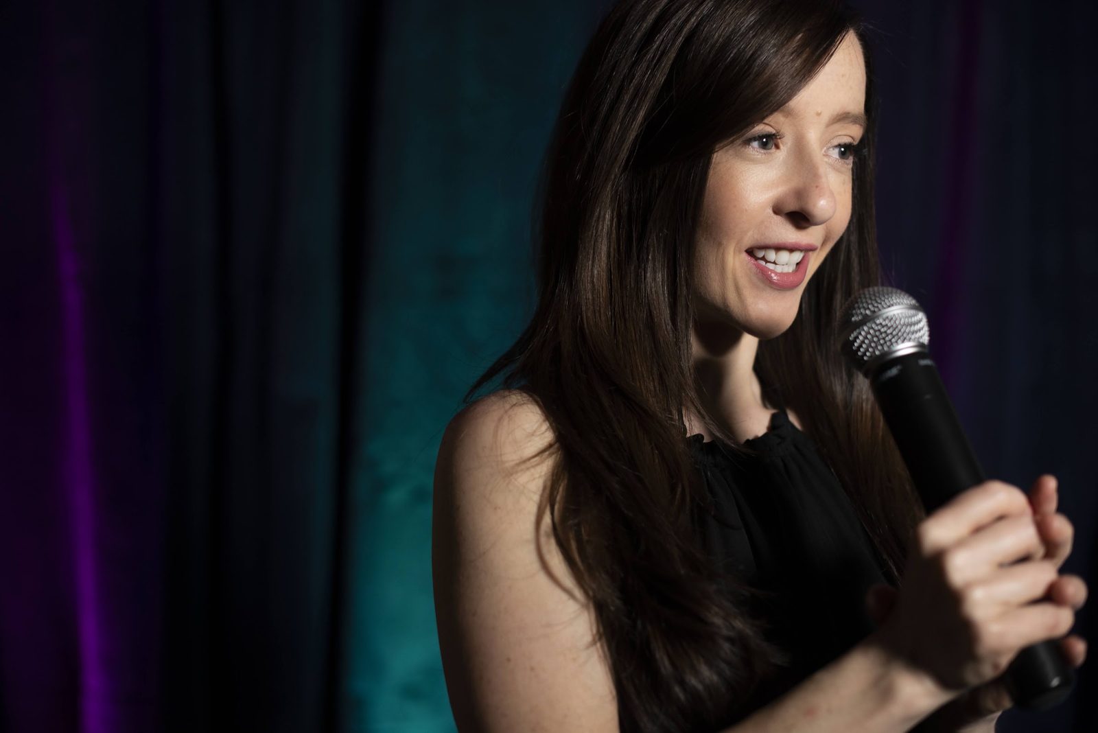 Mindie speaking on stage with a microphone