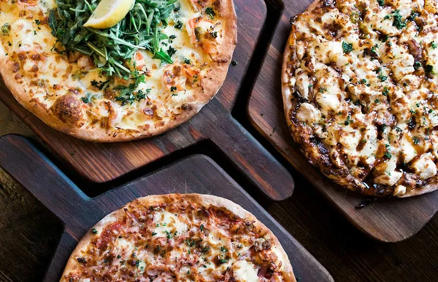 Three pizzas on timber boards, shot from above