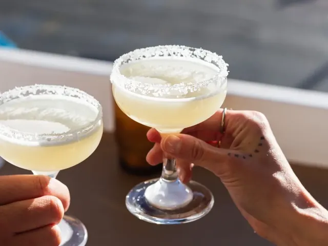 Two salt-rimmed coupe cocktails clinked in the sun