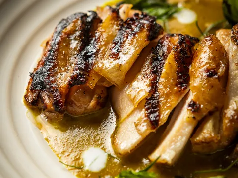 Close-up of sliced grilled kai yang chicken in sauce
