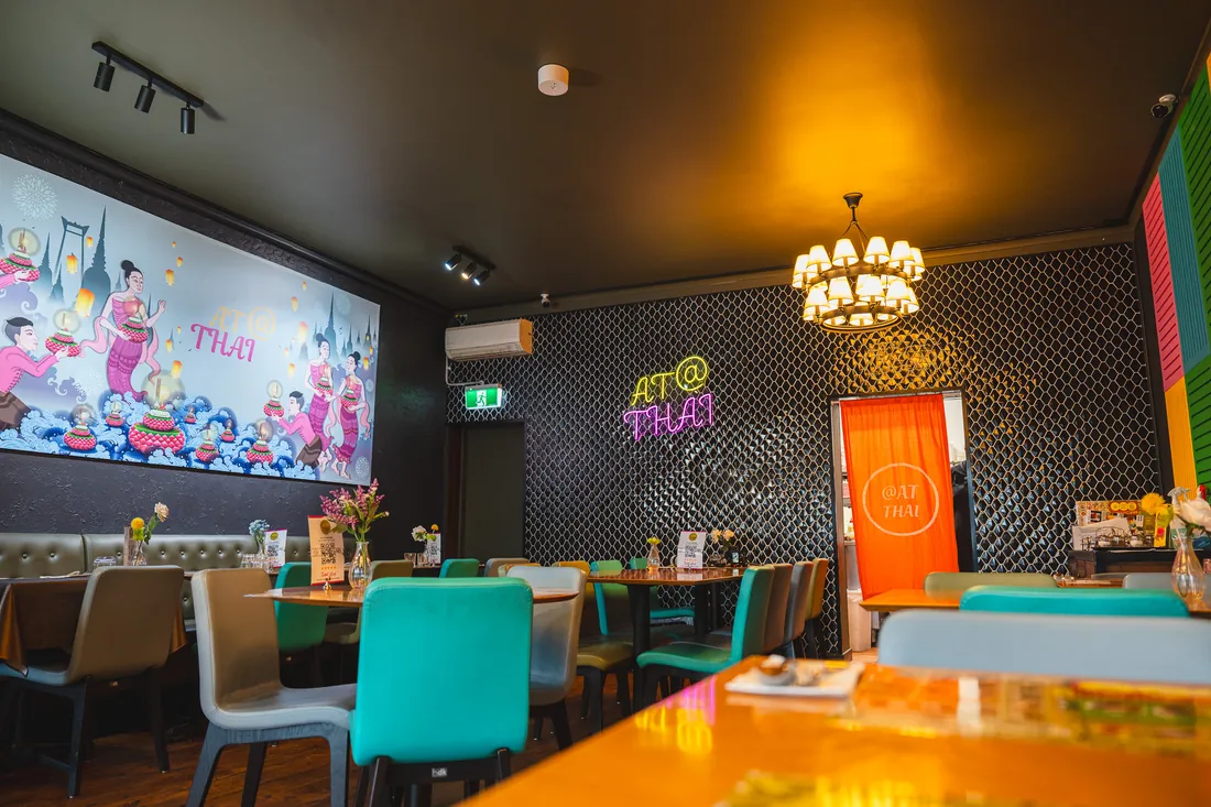 At Thai Lindfield&rsquo;s dining room: teal chairs, a mural wall and neon over the pass