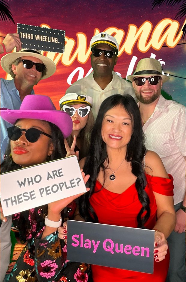 Guests with novelty signs and props at a Havana Nights themed photo booth