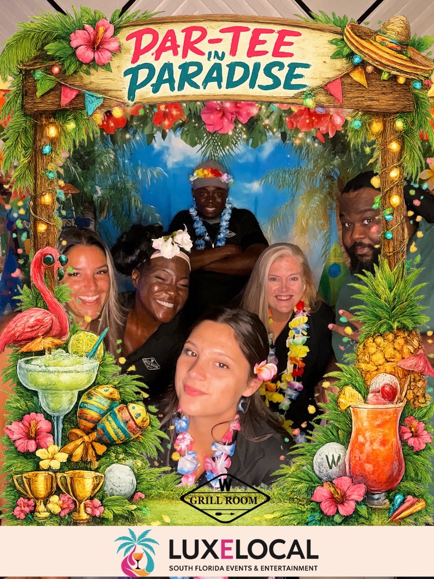 A group posing under the Par-Tee in Paradise photo booth frame at the W Grill Room