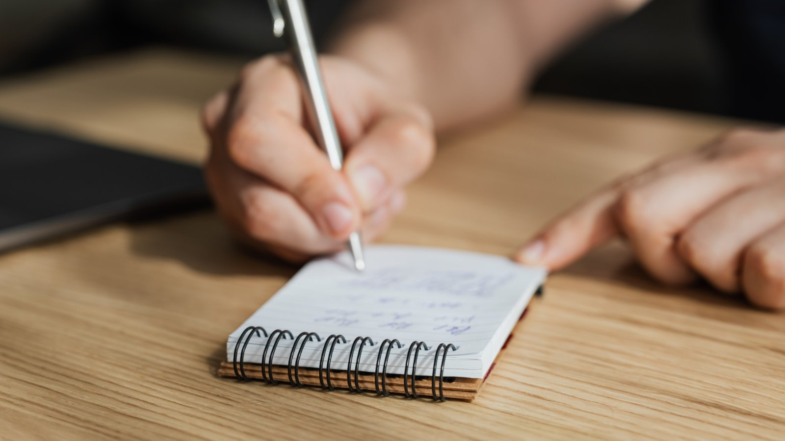 Hand writing notes in a small notebook