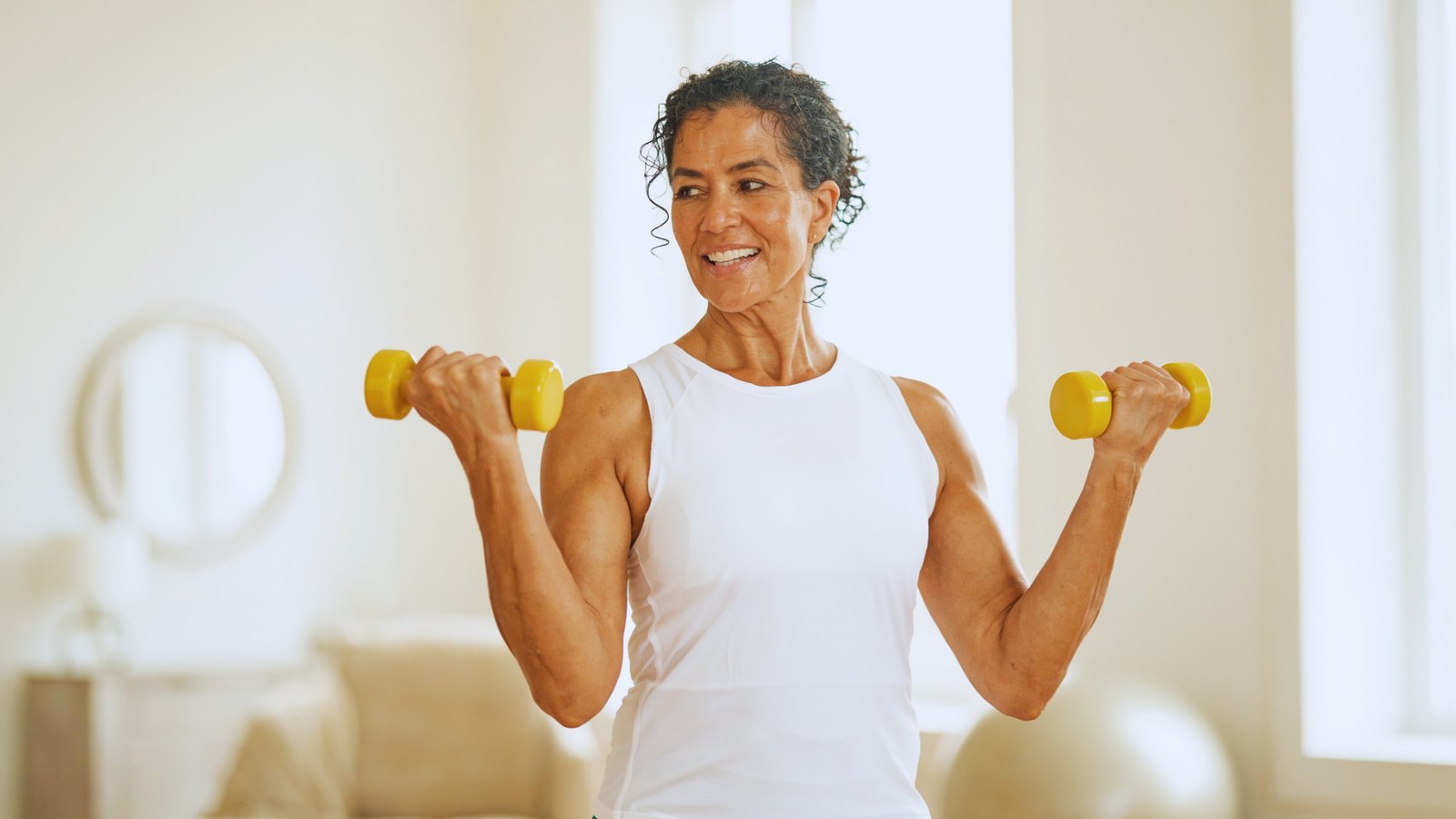 Woman smiling while lifting dumbbells